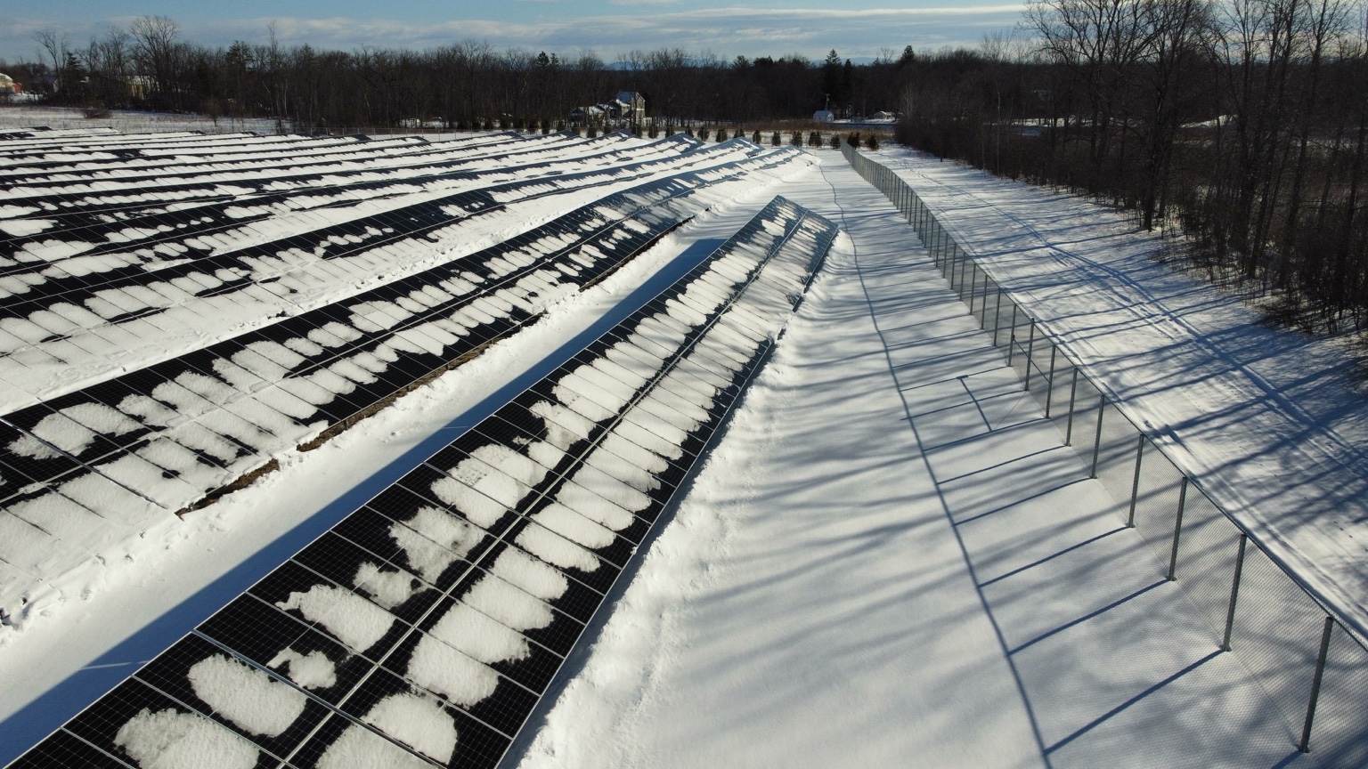 Actual February drone photo of snow-covered solar panels and tree shadows affecting the array